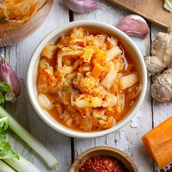 Bowl of kimchi with ingredients around it