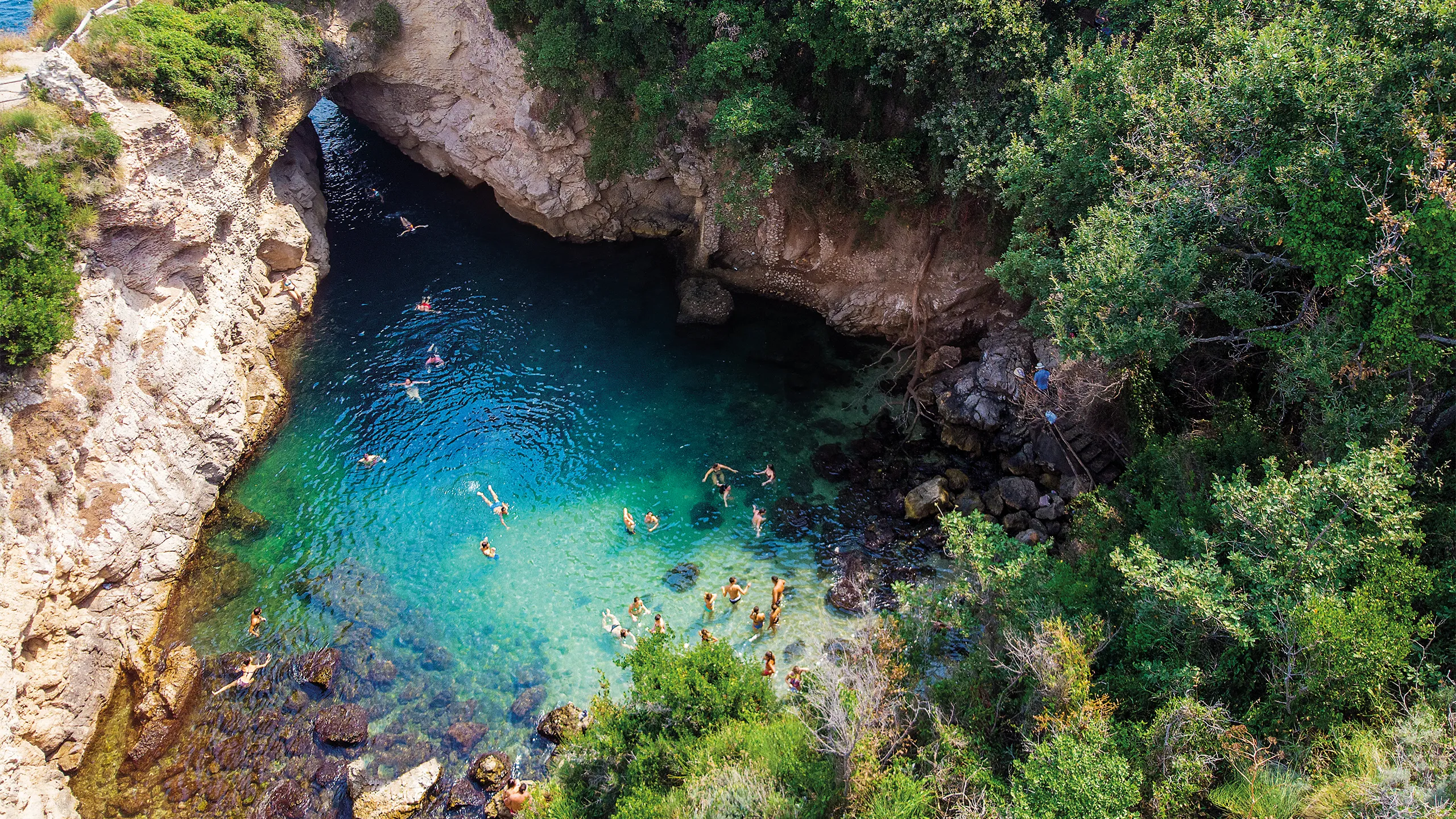 People bathing in a cove in Bagni Regina Giovanna, Italy