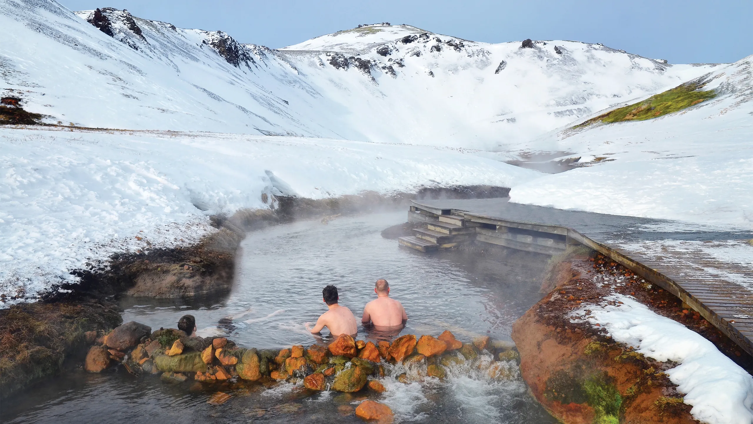 Two men enjoy a Icelandic thermal river.