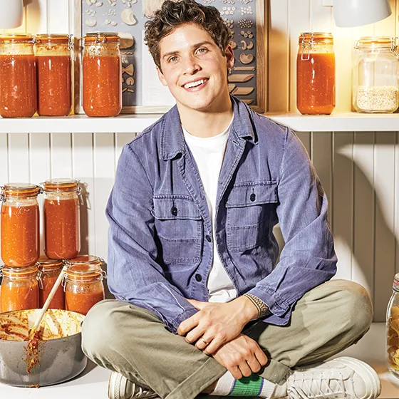 Portrait of Max sitting with shelves of kimchi