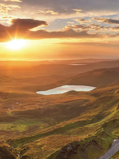 Scenic image of a road leading through the hills and a lake in the distance