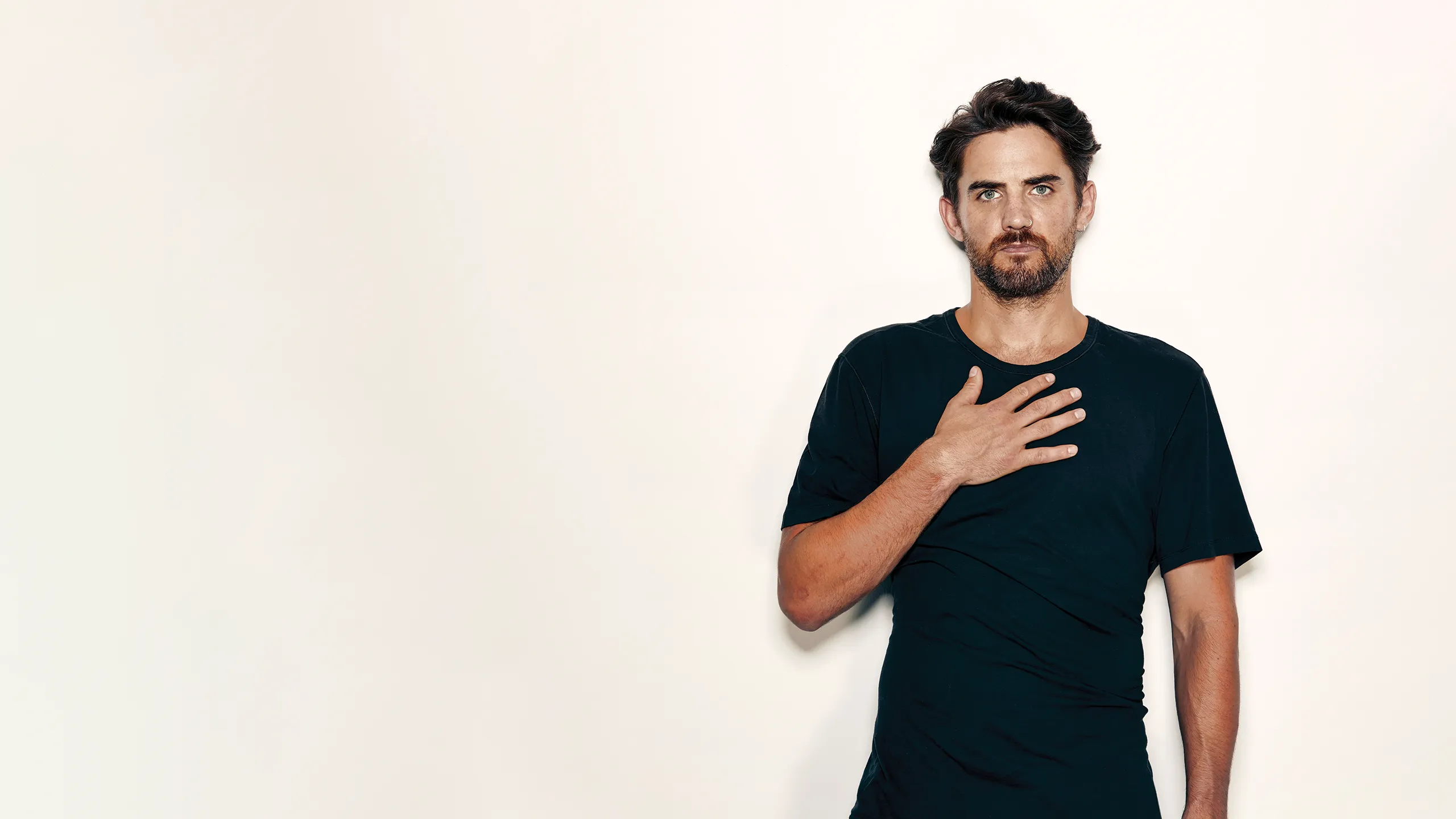 Portrait of Stuart Sanderman on a light backdrop with his hand on his heart area