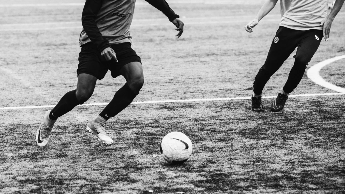 Grassroots football being played on a very muddy grass pitch ground level