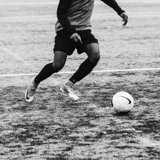Grassroots football being played on a very muddy grass pitch ground level
