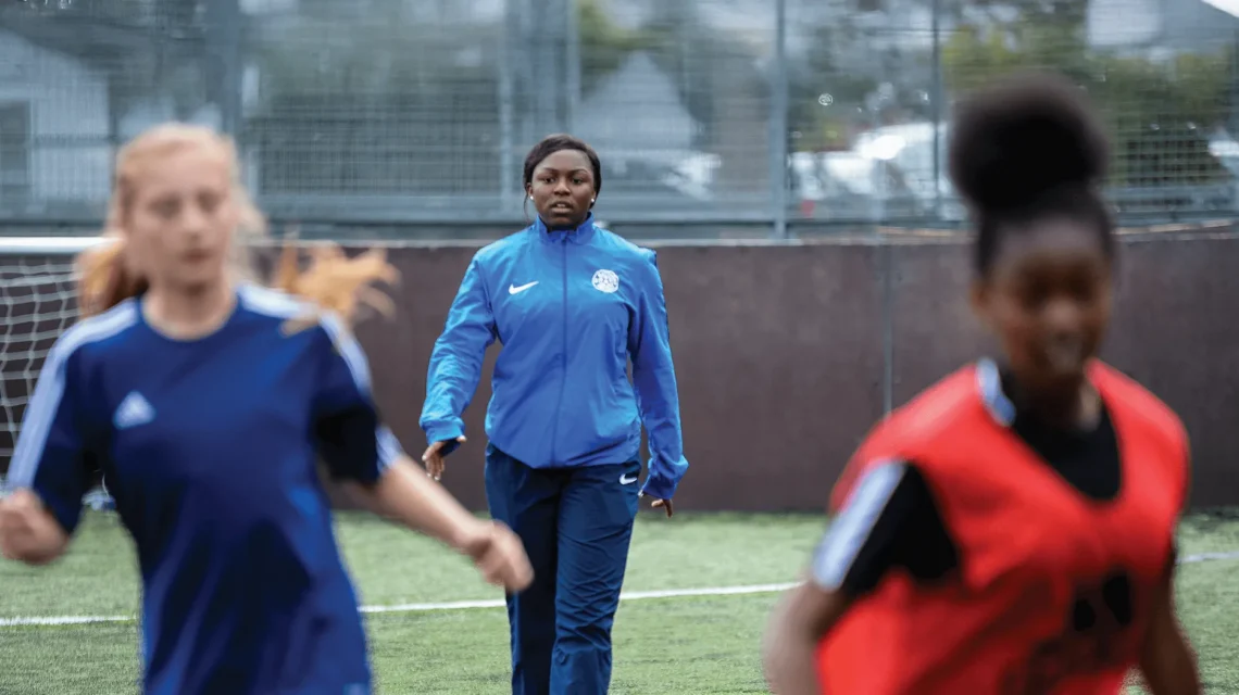 Mid 20s black woman coaching female football team in England