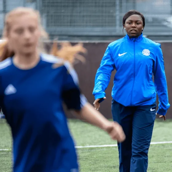 Mid 20s black woman coaching female football team in England
